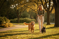 Woman walking a golden retriever and a French bulldog on a sunny tree-lined park path
